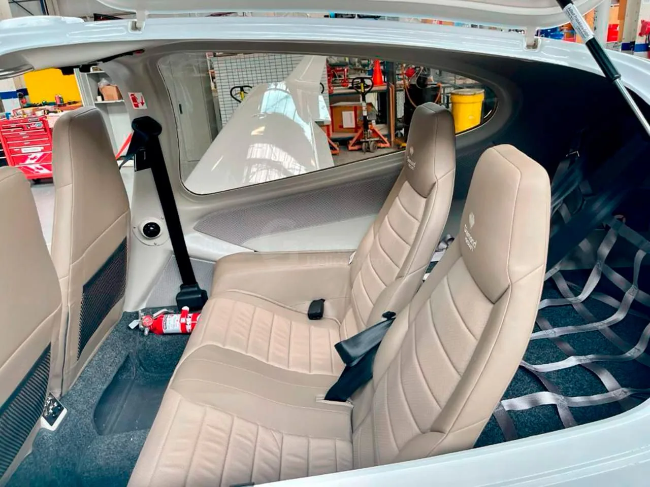 The rear tan leather seats and cargo net in the interior of a Diamond DA40 aircraft.