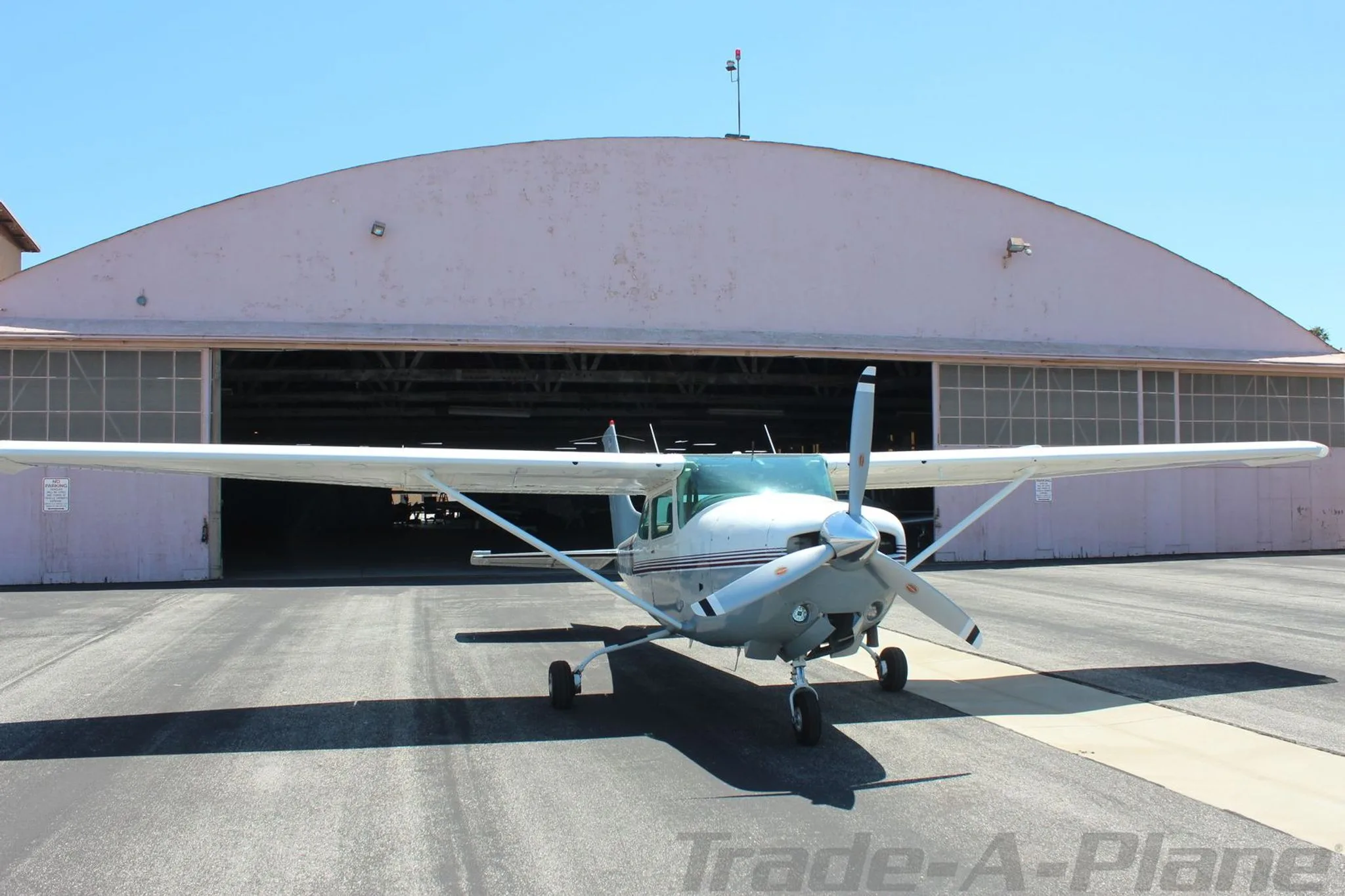 A Cessna TR182 parked in front of a hangar.