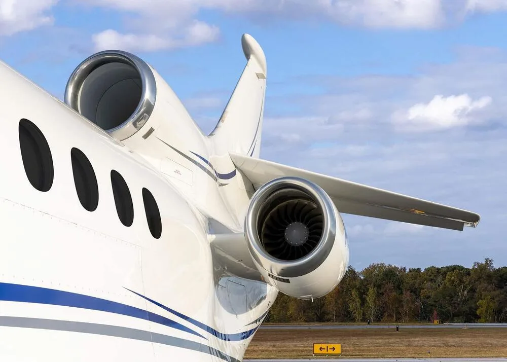 A close-up view of the rear fuselage and engines of a white Dassault Falcon business jet.