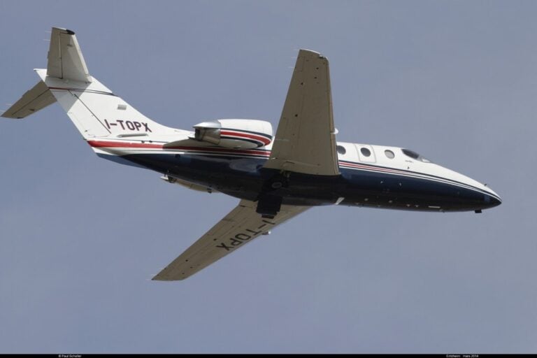 A white jet with tail number HA-YFH flying in a blue sky.