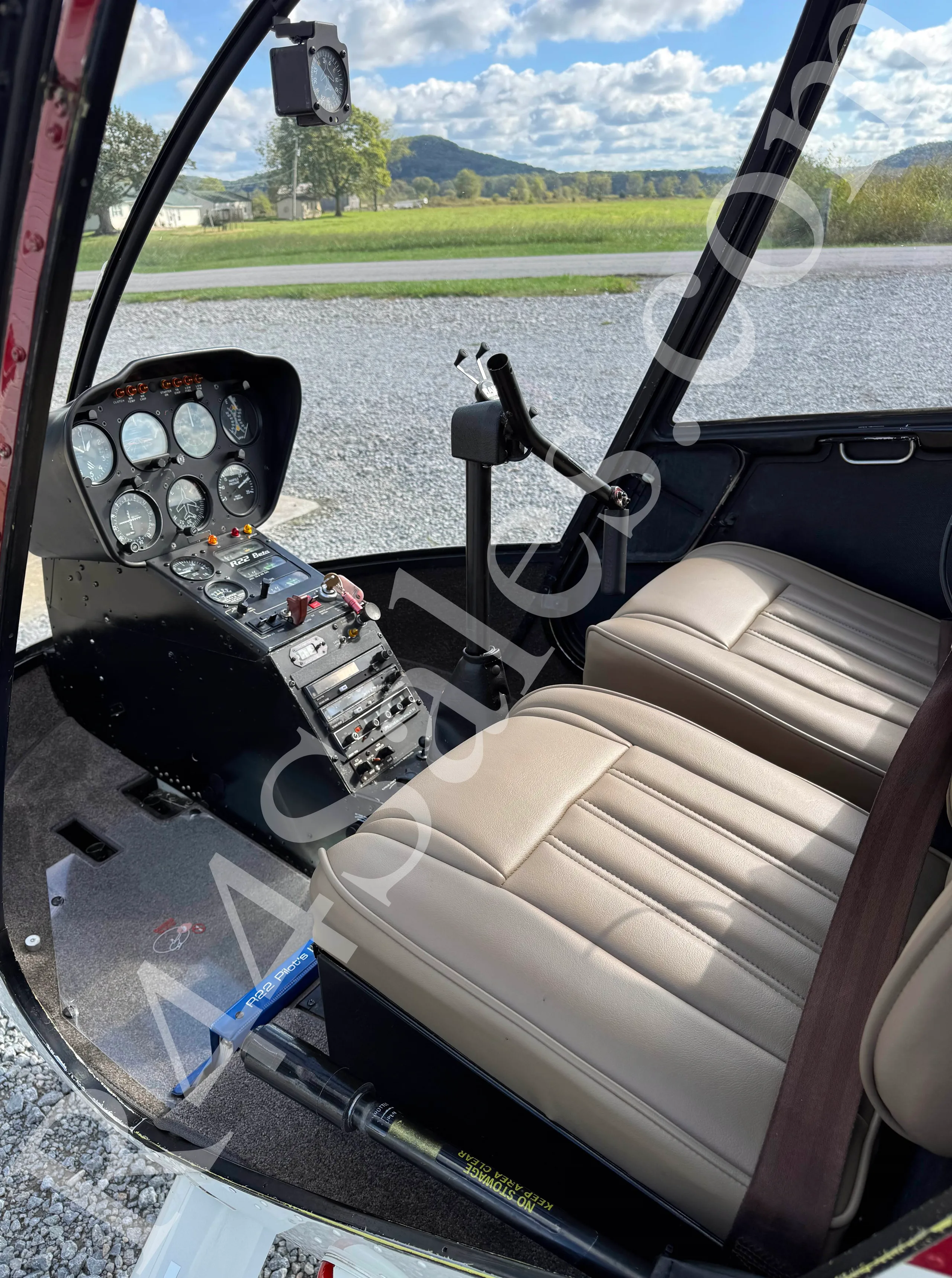 The cockpit of a Robinson R22 helicopter showing the instrument panel and tan seats.