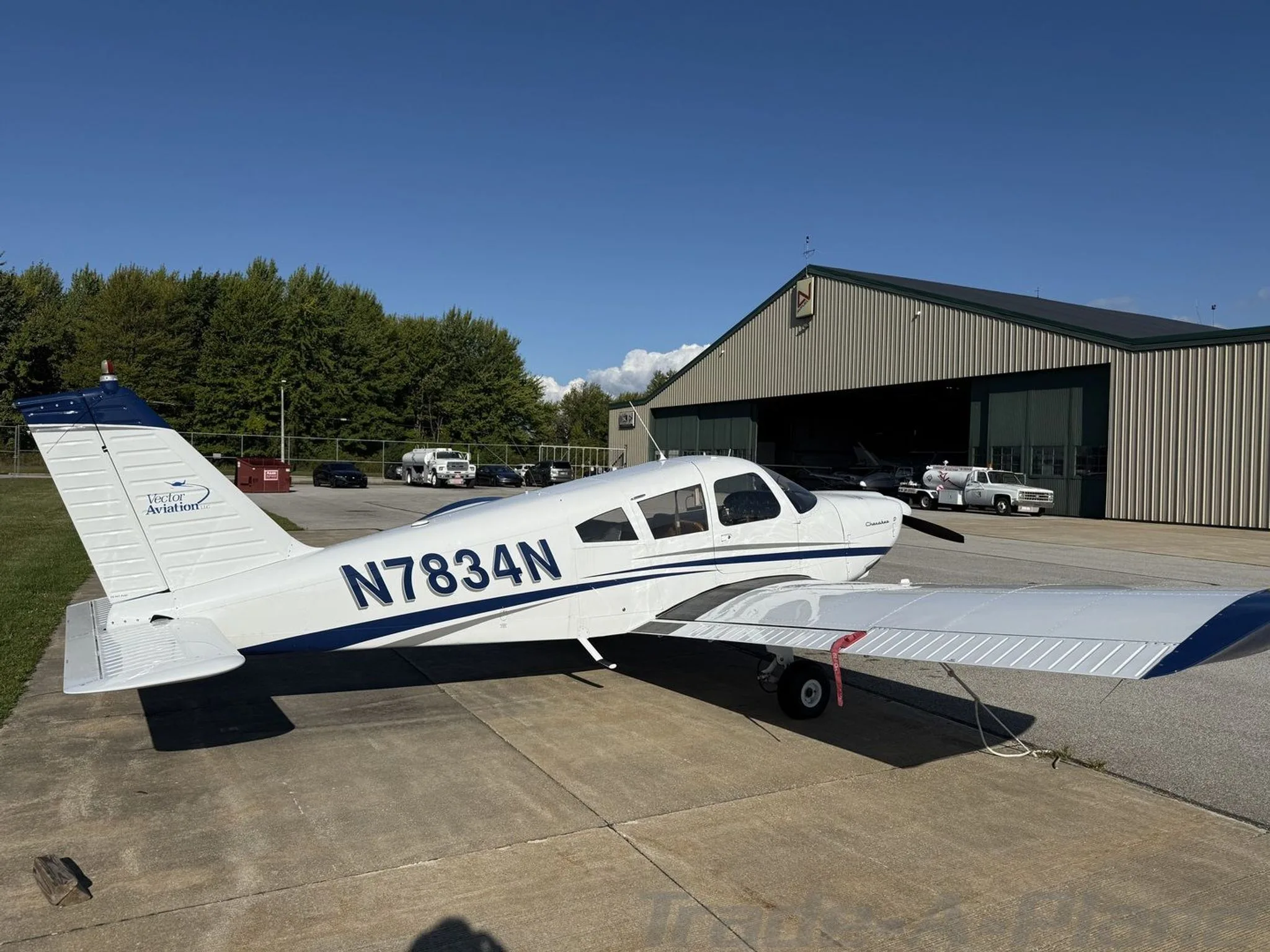 A side view of the aircraft parked near a hangar.