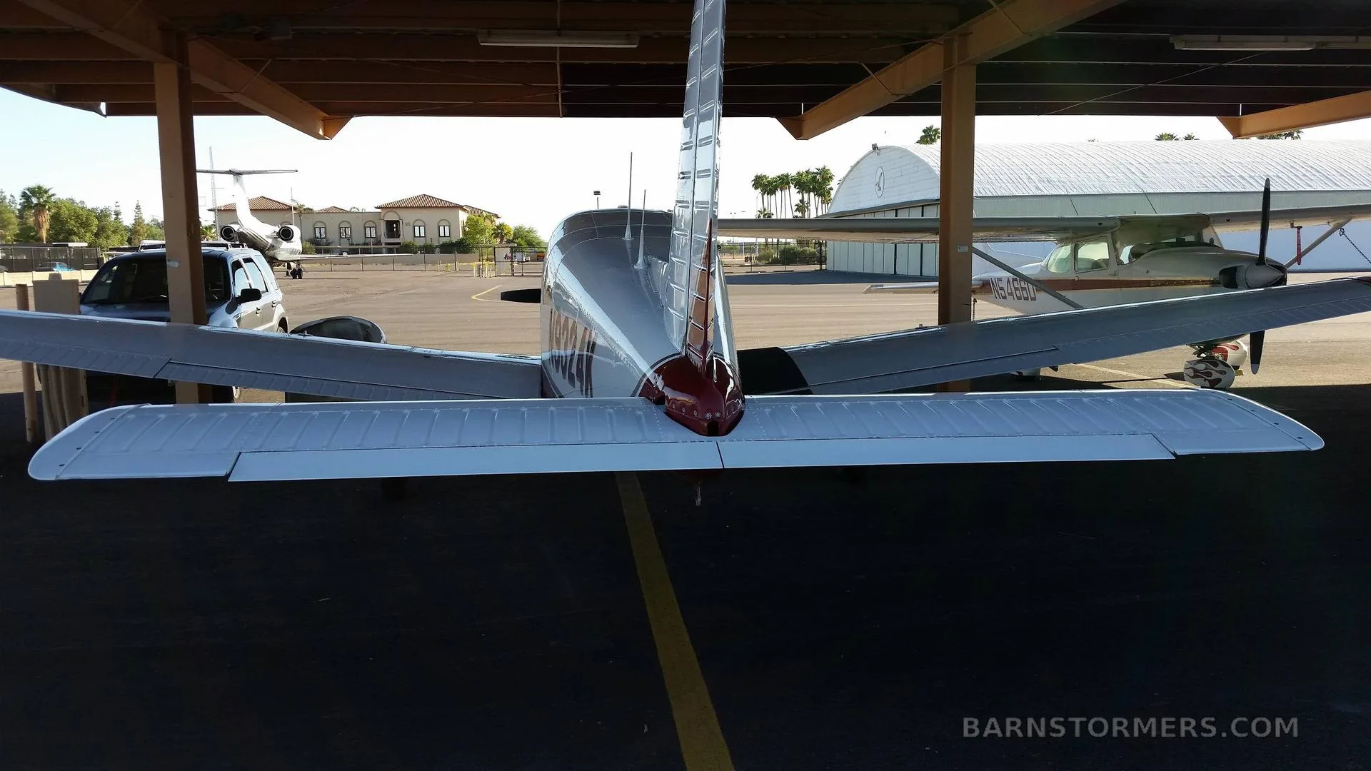 A rear view of a white and red Piper Archer II, showing its tail and horizontal stabilizer under a hangar.