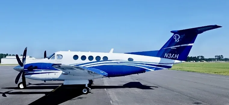 A white and blue Beechcraft King Air 350i aircraft with tail number N3AH parked on an airfield.