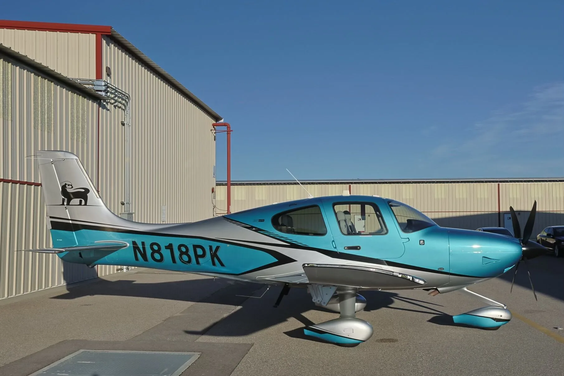A side view of a teal and silver Cirrus SR22T GTS aircraft (N818PK) parked on an airfield.