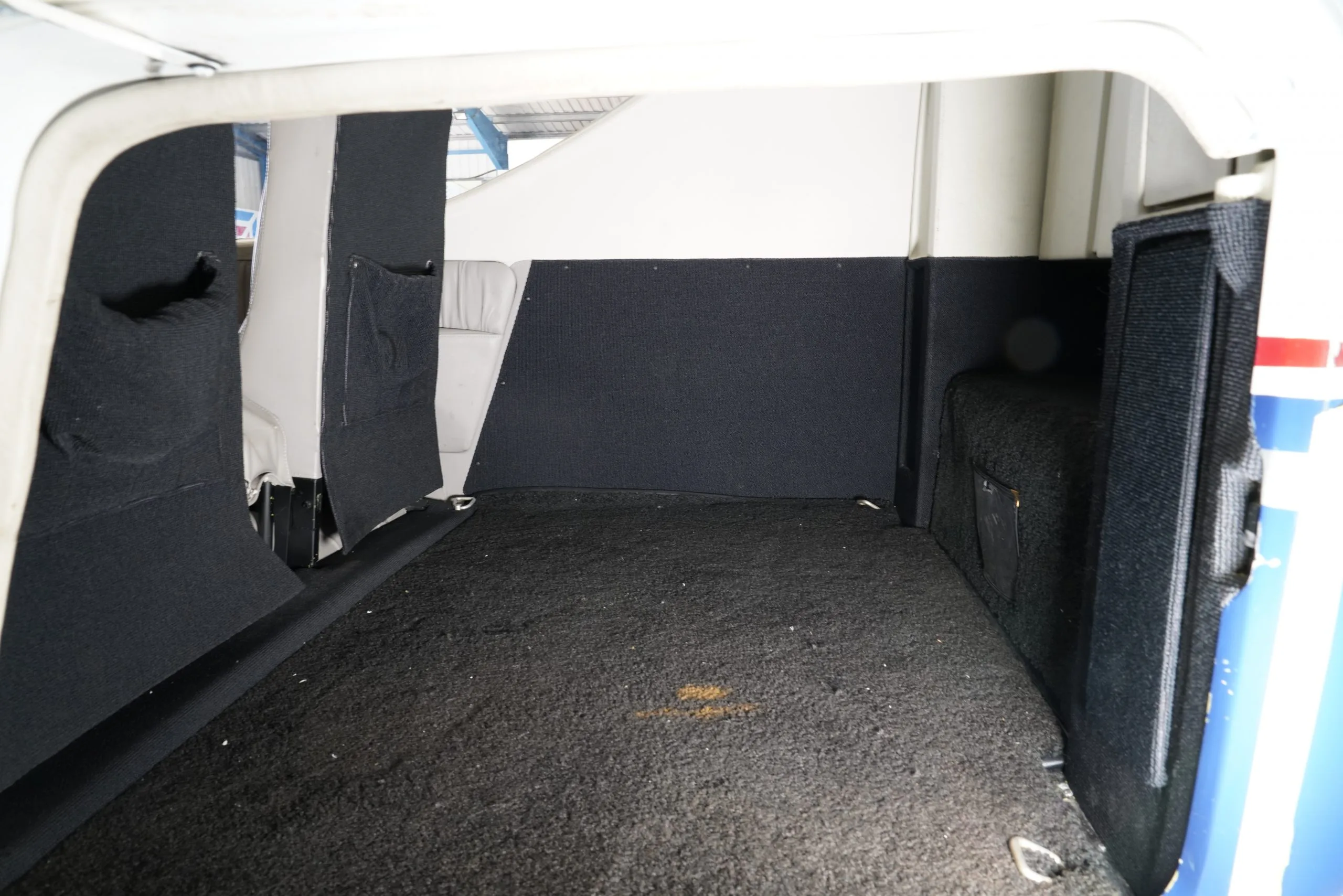 The carpeted baggage compartment of the aircraft, with black side panels.