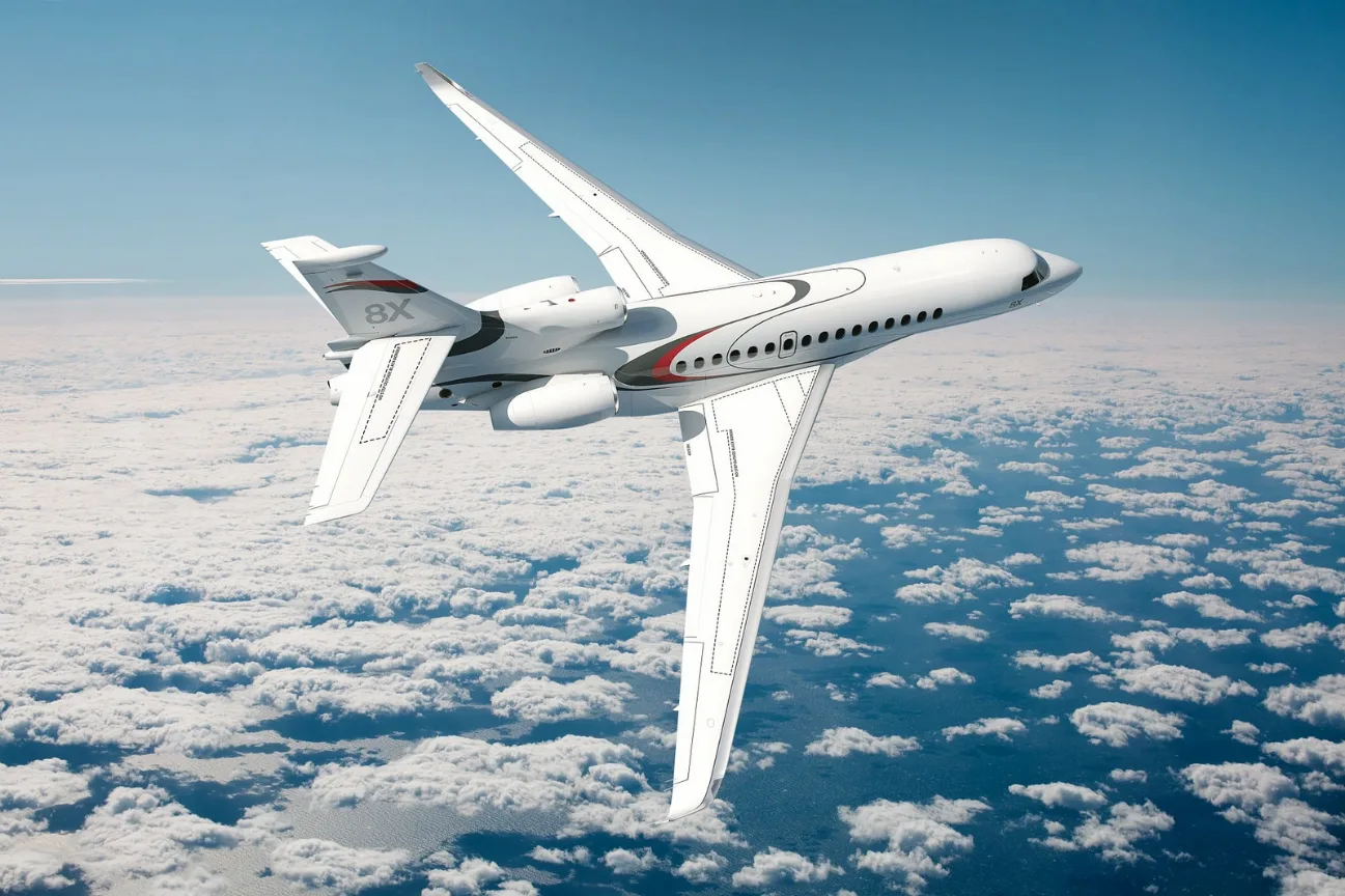 A Falcon 8X jet flying above the clouds.