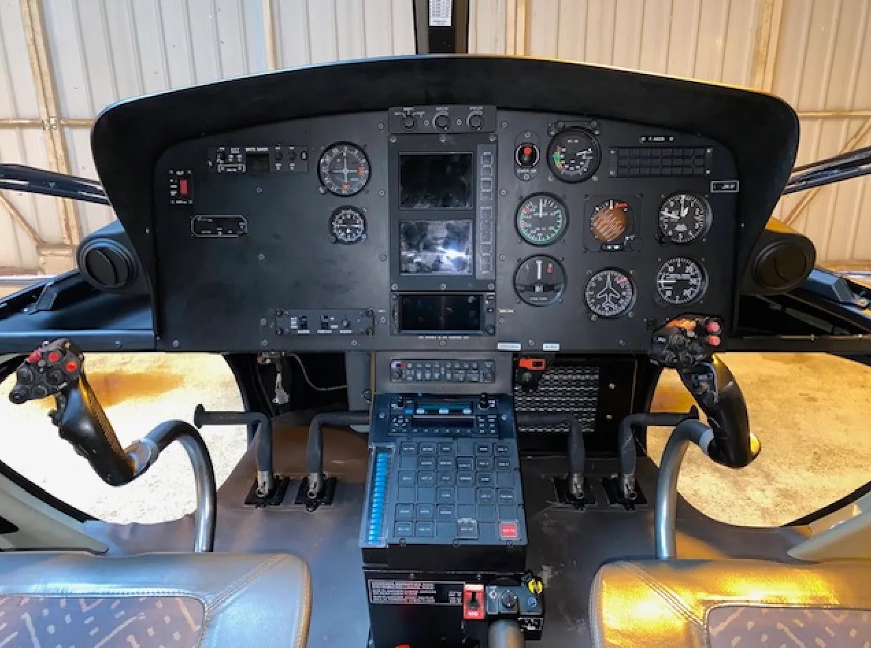 Helicopter cockpit instrument panel with various gauges and controls.