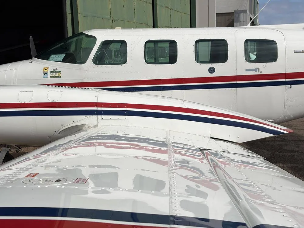 A close-up view of the fuselage and wing of the N303WJ aircraft, showing its white, red, and blue paint scheme.