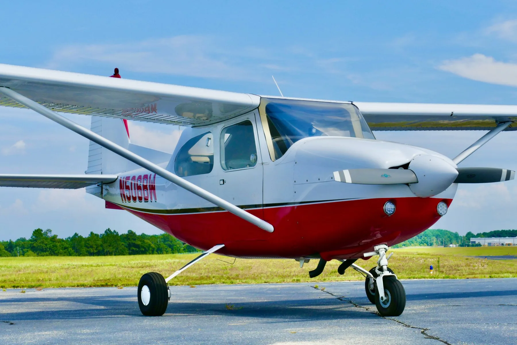 A front-left view of a white and red Cessna 172 aircraft, N506BW, parked on an airfield.
