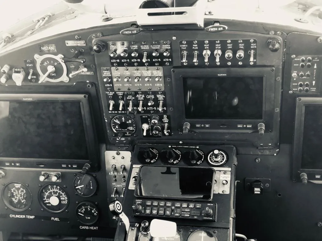 A black and white close-up of the Antonov AN-2 cockpit instrument panel with modern Garmin displays.