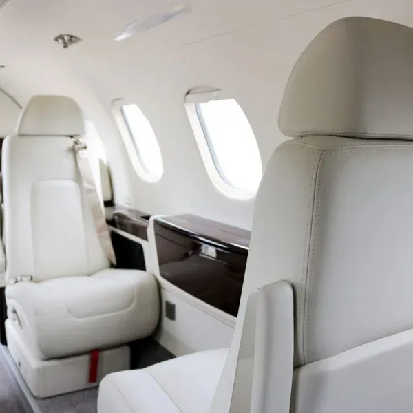 A side view of the private jet's interior cabin, showing white leather seats and windows.