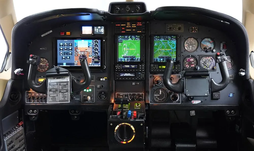 Detailed view of a modern aircraft cockpit with multiple digital displays and control yokes.