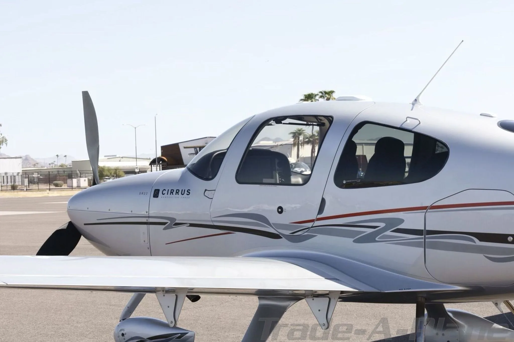 A close-up side view of the silver Cirrus SR22 aircraft's fuselage and cockpit windows.