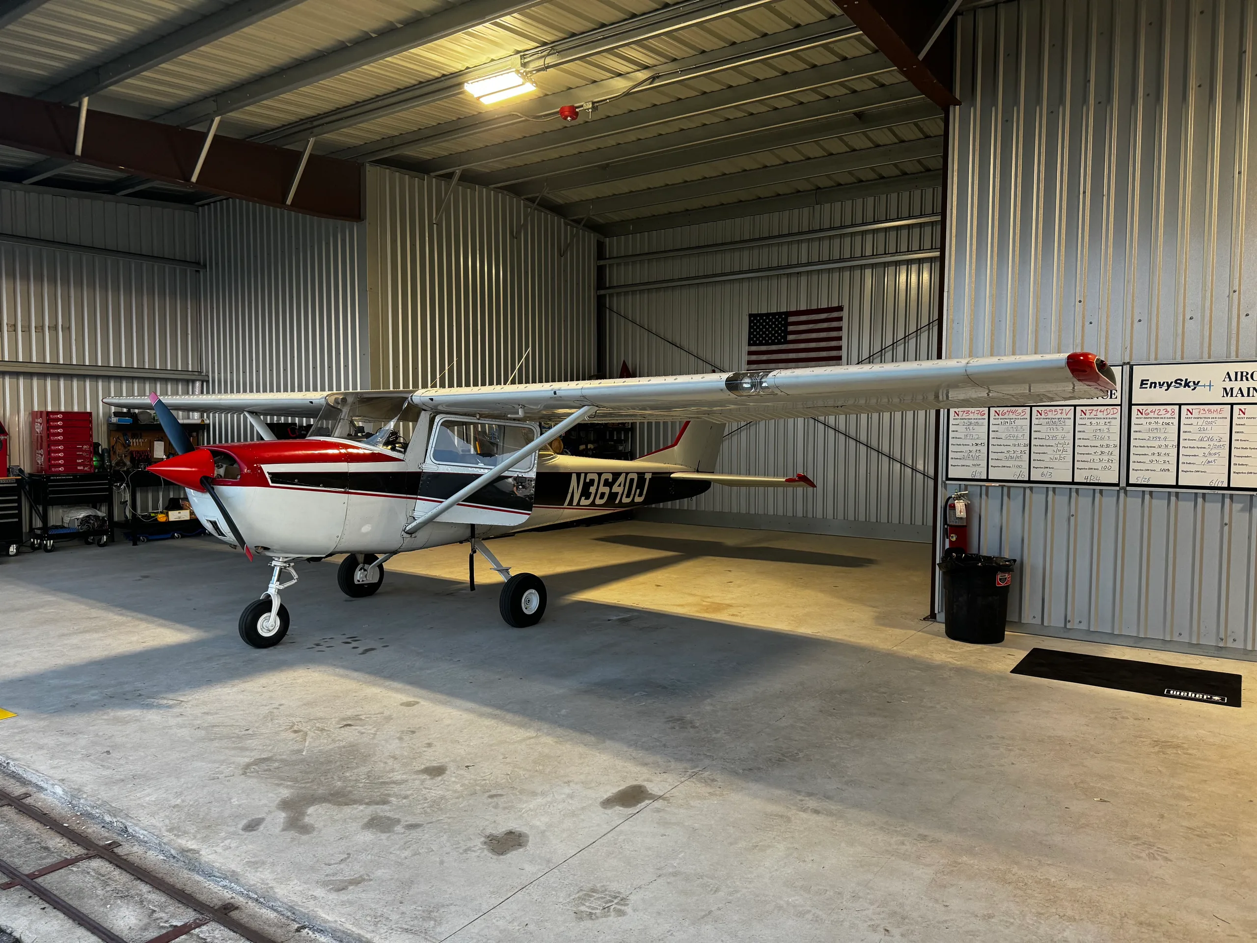 A white and red Cessna 172, N3640J, with a black stripe, parked in a hangar.