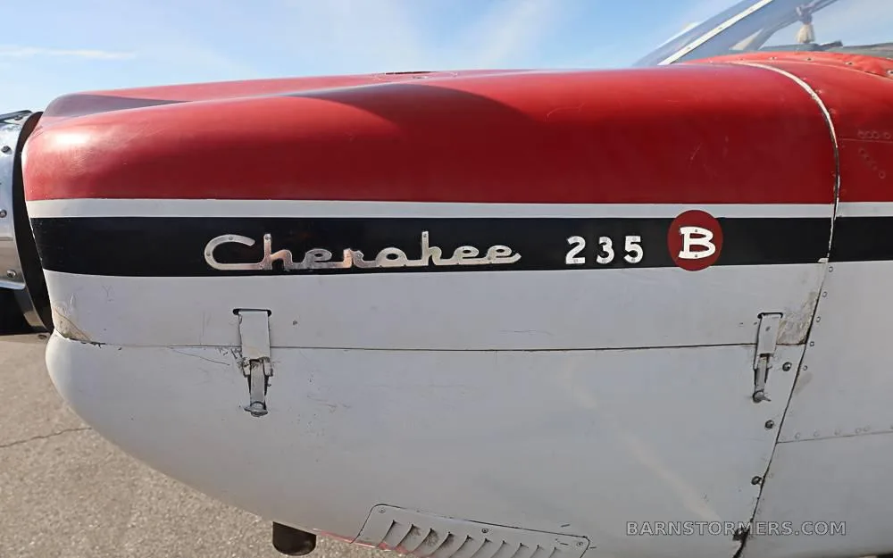Close-up of the red and white fuselage of a Piper Cherokee 235 B, showing the model name painted on the side.