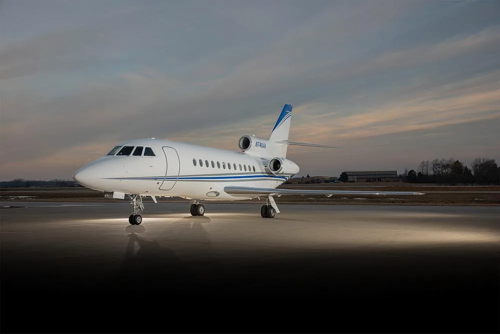 A Dassault Falcon 900EX business jet with registration N746AR is parked on an airport tarmac under a cloudy sky.