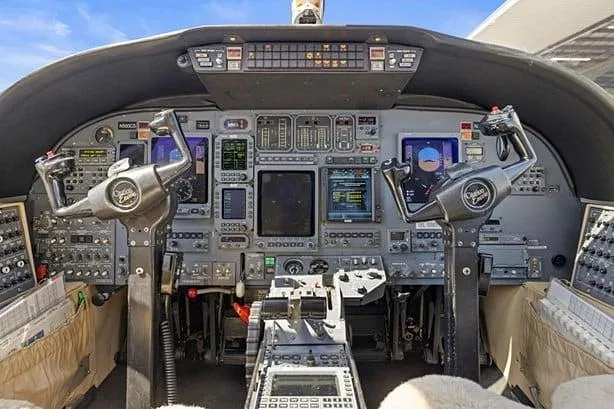 The cockpit of a Cessna Citation CJ3, showing the instrument panel, yokes, and center console.