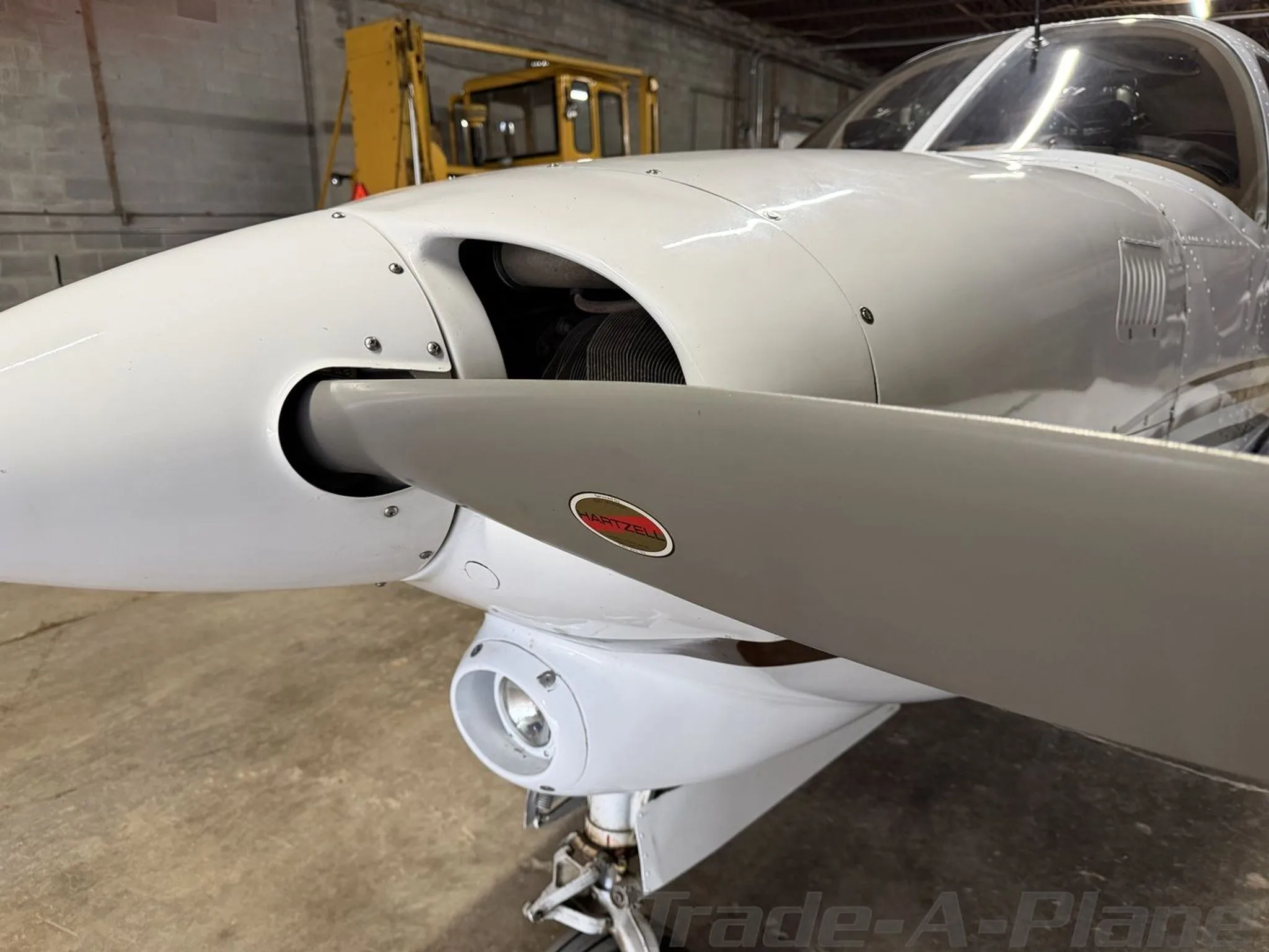 A close-up view of the propeller and nose of the white Piper aircraft N41GF in a hangar.