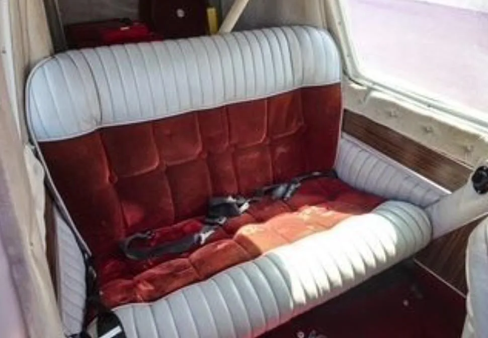 The red velvet and white upholstered rear bench seat of the aircraft cabin.