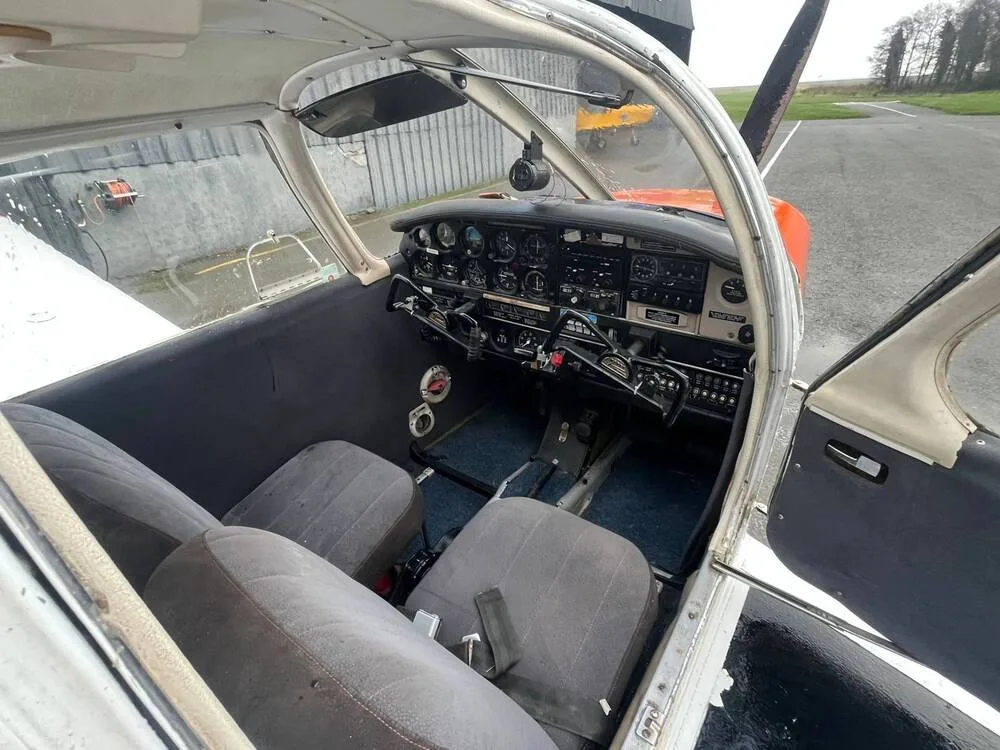 The interior cabin of the Piper Cherokee 140 (N228WF) showing the front seats and a partial view of the instrument panel.