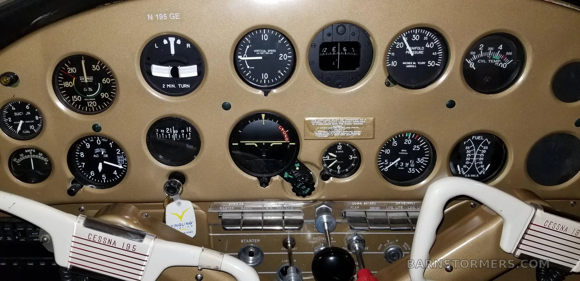 A close-up of a gold-colored aircraft instrument panel with various gauges and controls, including a 'CESSNA 195' label on the yoke.