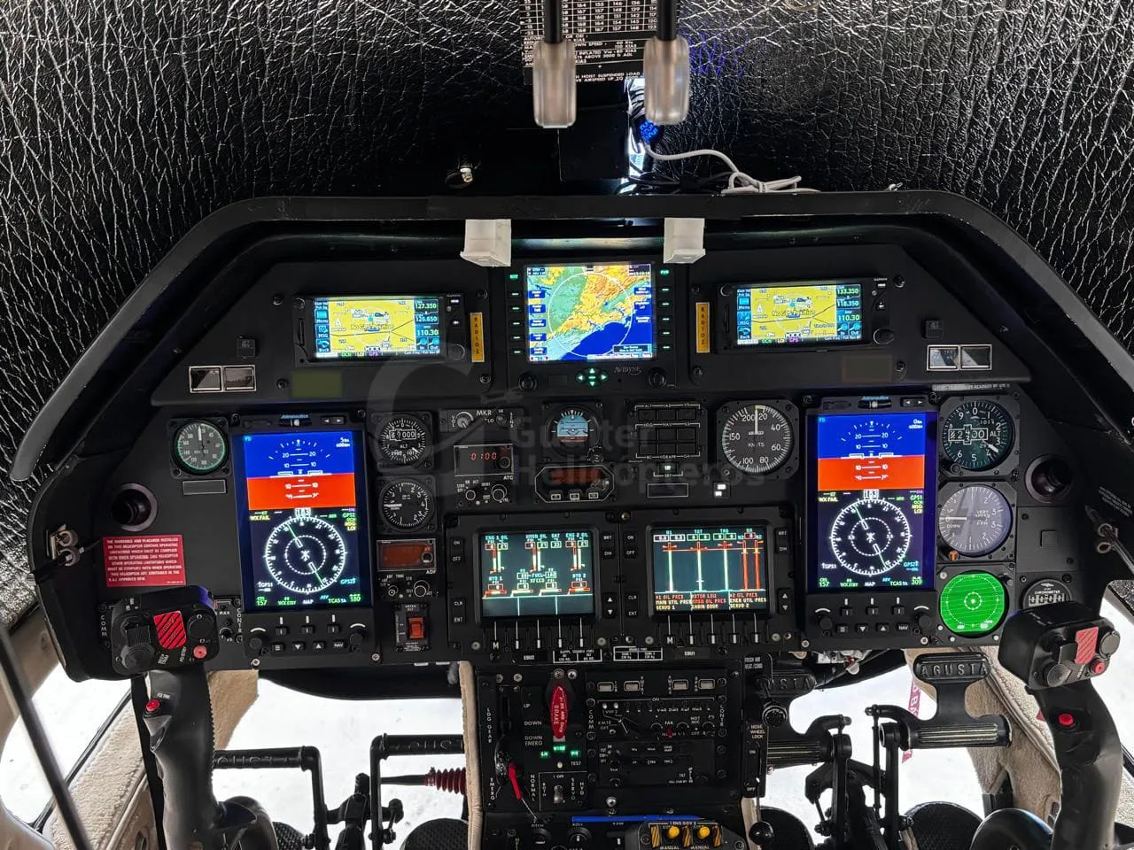 A detailed view of the Agusta A109 Power helicopter's modern glass cockpit with multiple digital displays and analog gauges.