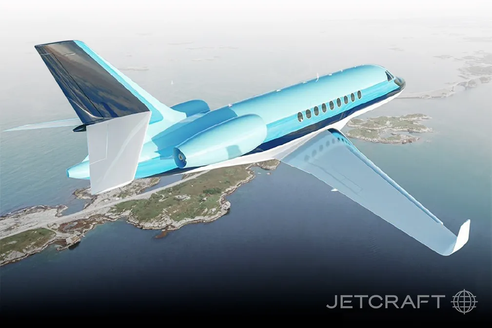 A light blue business jet with dark blue accents flies over a coastal landscape.