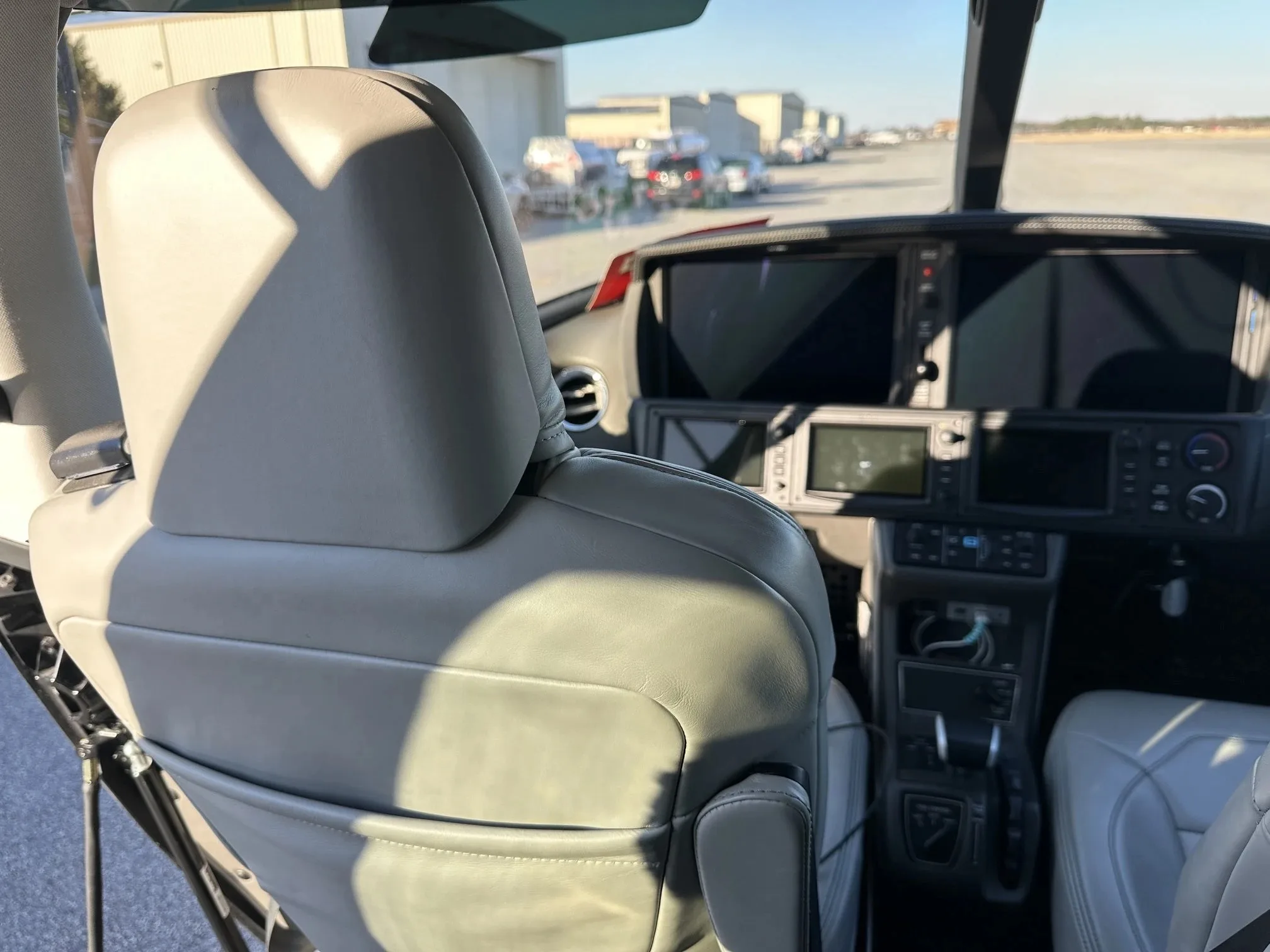 View from the rear of the pilot's seat in a Cirrus Vision Jet cockpit, showing the instrument panel and front passenger seat.