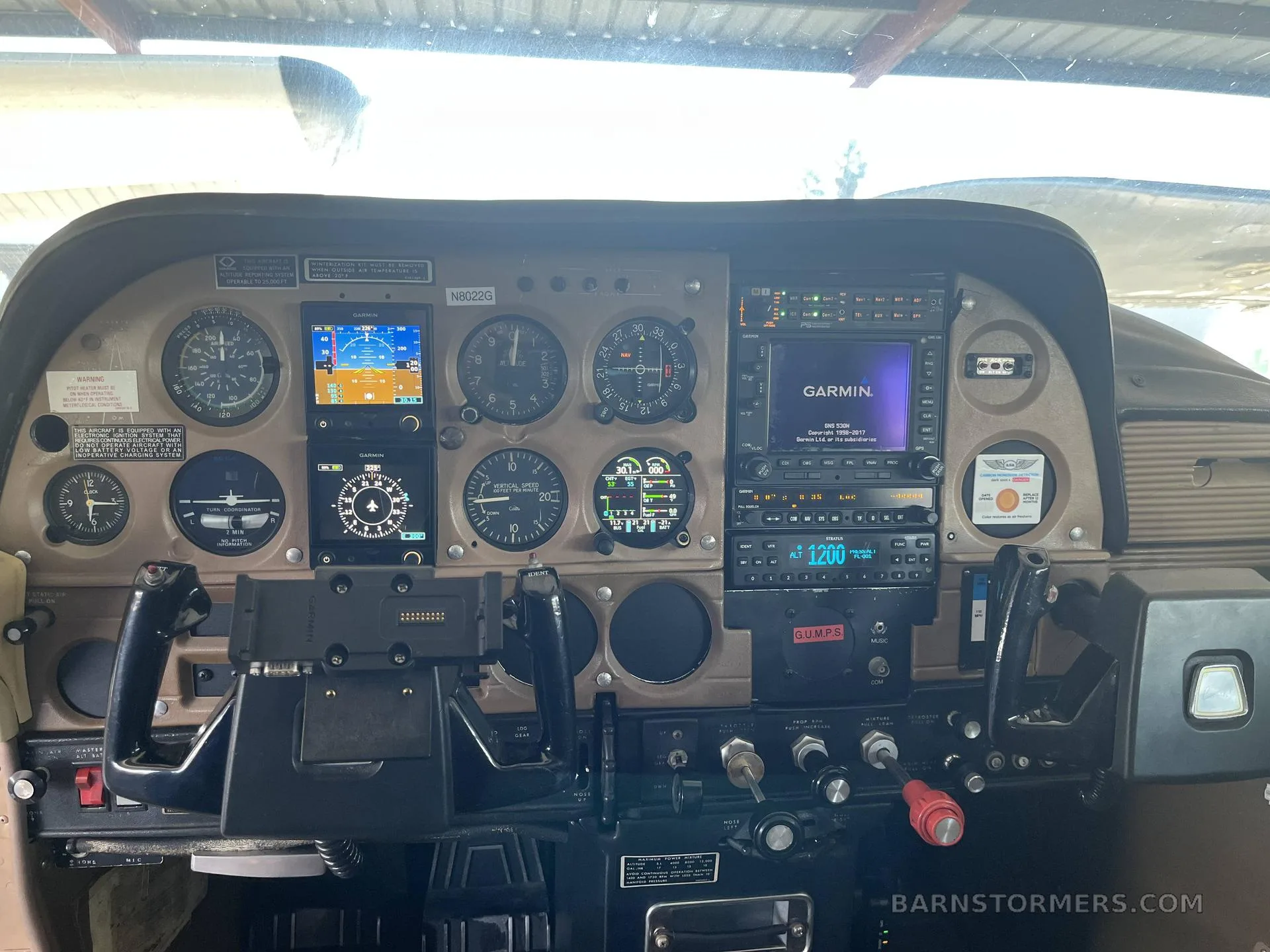 The cockpit instrument panel of a Cessna 182 aircraft, featuring both analog gauges and modern Garmin digital displays.