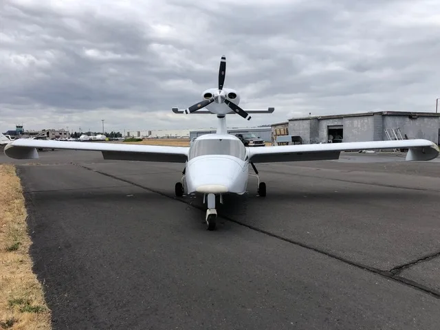 A white Searey amphibian aircraft, N9004T, is parked on an asphalt runway, viewed from the front.