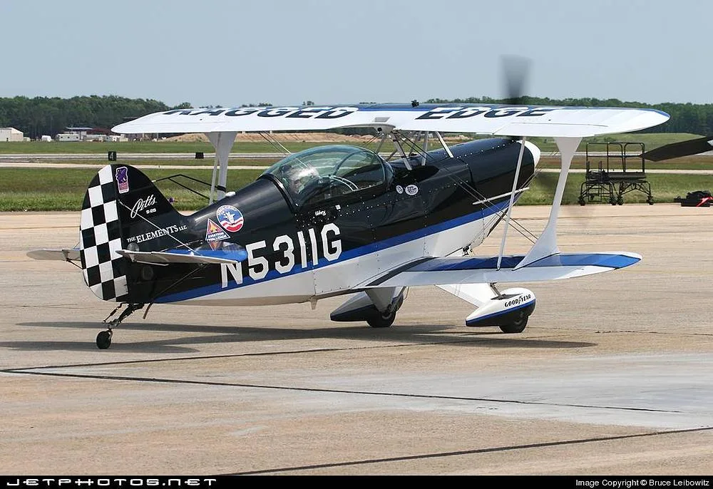 A black, white, and blue Pitts biplane with registration N5311G is parked on an airfield tarmac.