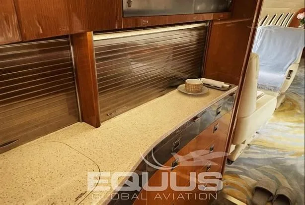 A close-up view of a private jet's galley area with a countertop, storage, and a cup.