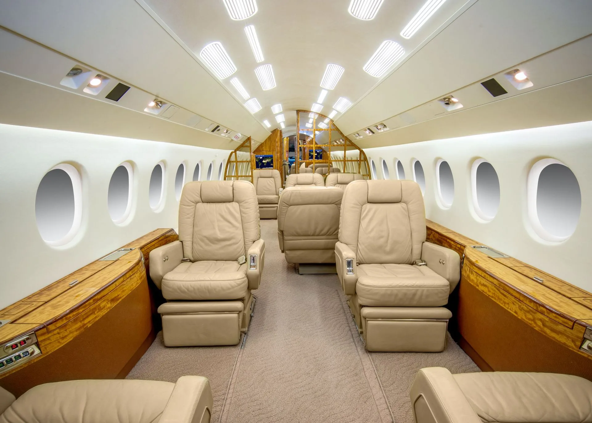 The aircraft's main cabin with beige leather seats arranged in a club configuration and large oval windows.