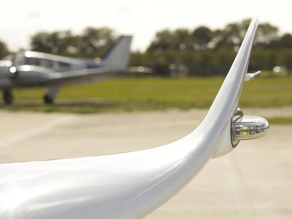 A close-up of the wingtip with navigation lights of the Cessna Citation M2, N440LN, with another aircraft blurred in the background.