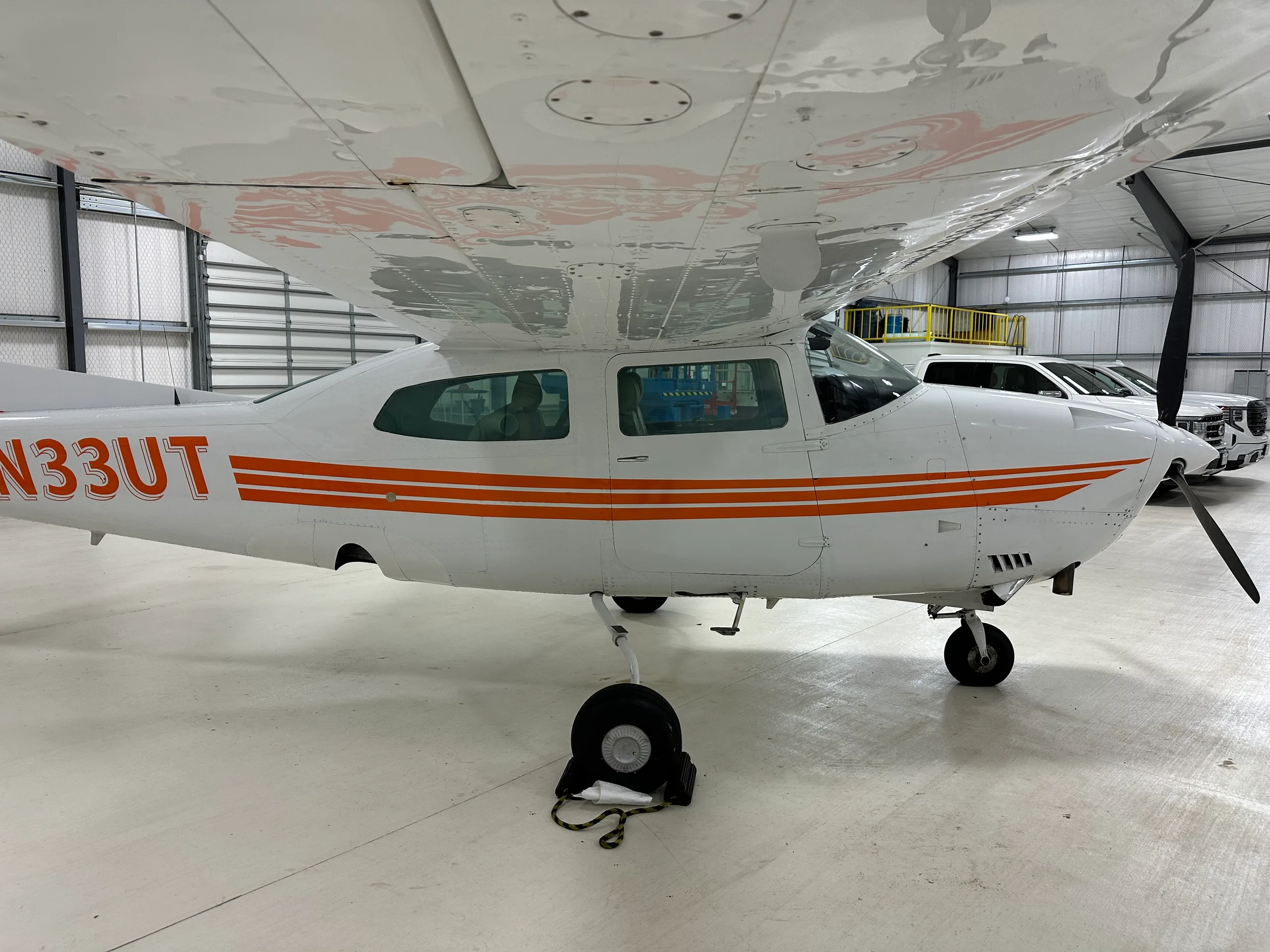 A Cessna 206 Stationair aircraft with orange stripes parked in a hangar.