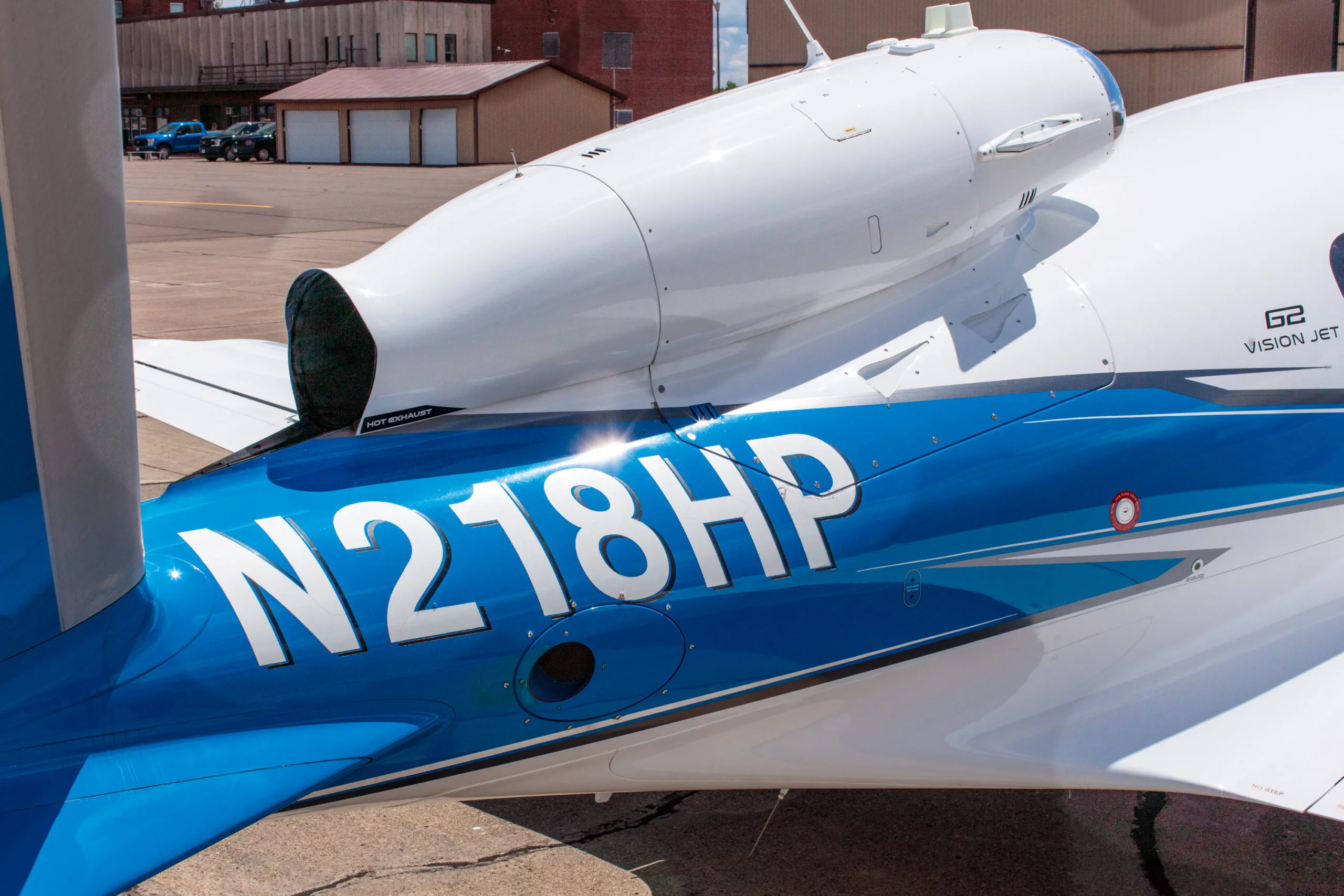 Close-up of the tail section of the Cirrus Vision Jet (N218HP) showing the engine and blue livery.