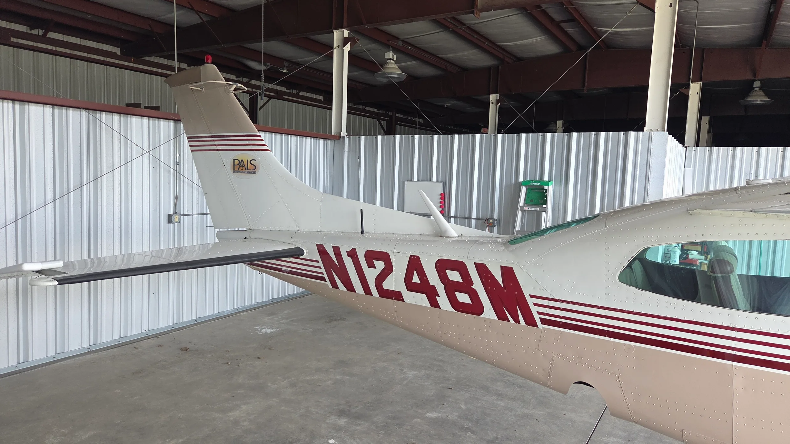 A close-up view of the tail section of a white and tan aircraft, showing the N1248M registration and a "PAIS" logo.