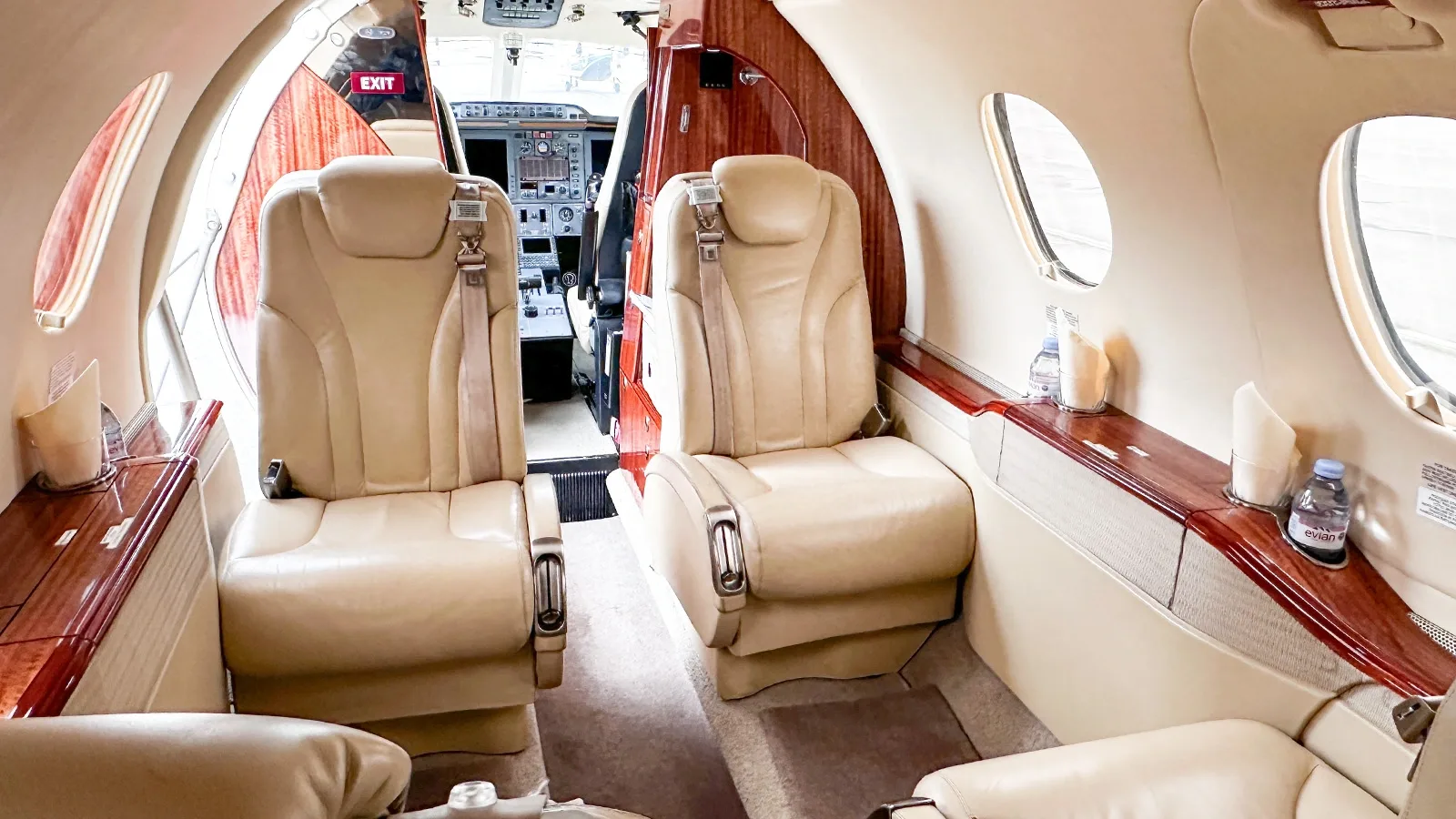 The luxurious beige leather interior cabin of a business jet, looking towards the cockpit.