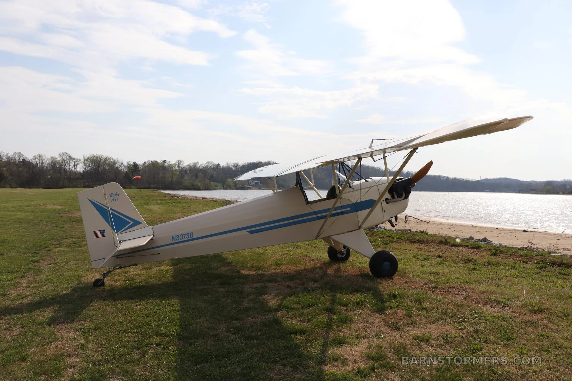 The cockpit of a light aircraft with a blue instrument panel, wooden floorboards, and a single seat.