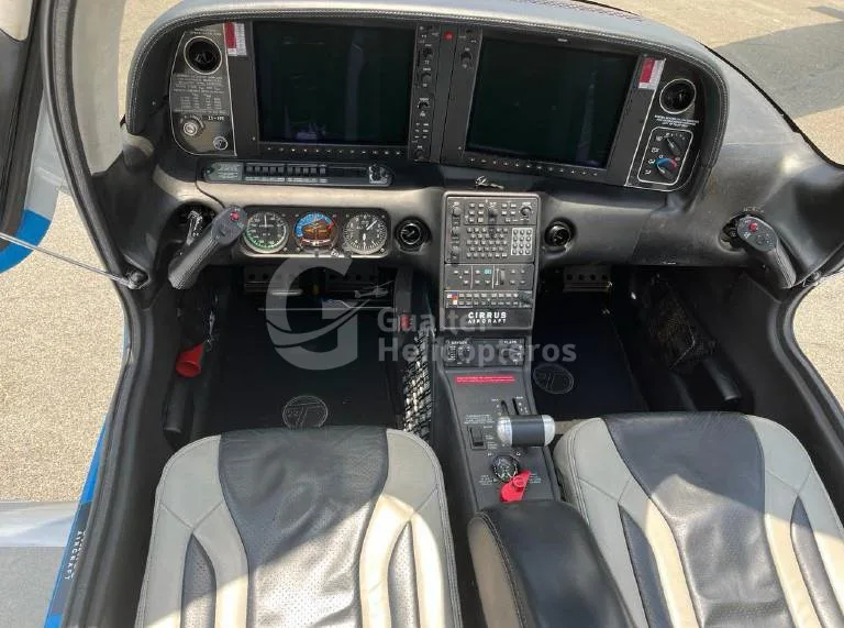 The cockpit of a Cirrus SR22 aircraft, featuring a glass panel display, control yokes, and black and grey leather seats.