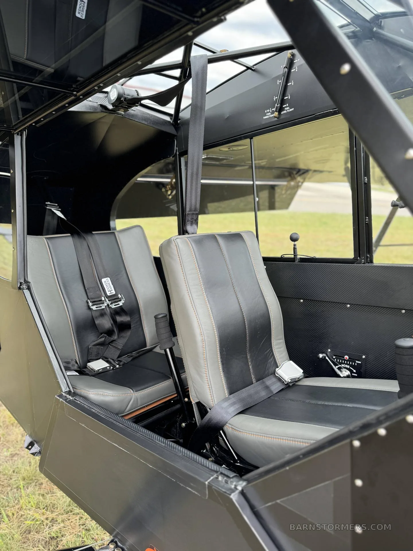 The interior of the black Super Cub, showing two black and grey seats with seatbelts.