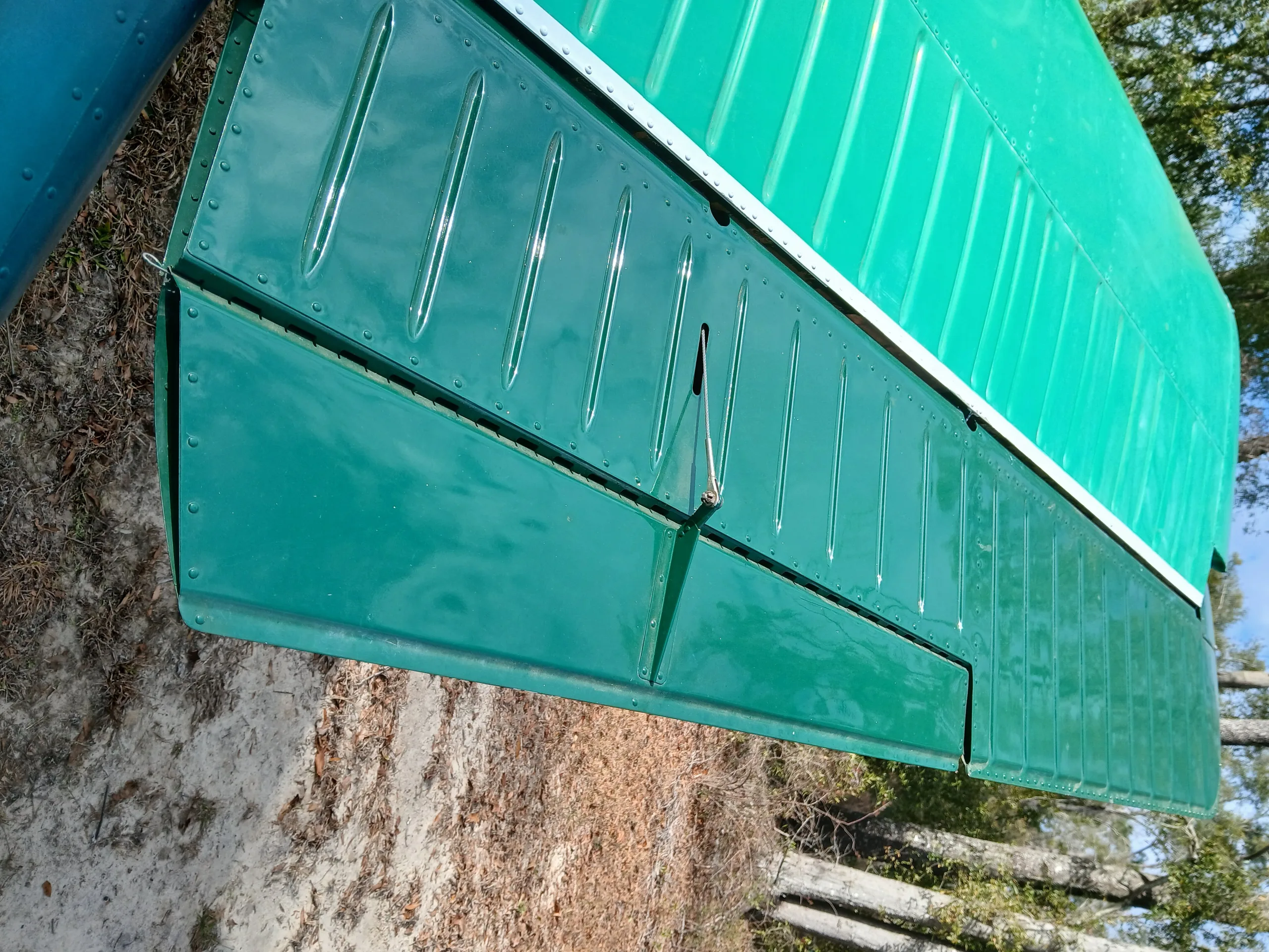 A close-up view of the green wing flap and aileron of an aircraft.
