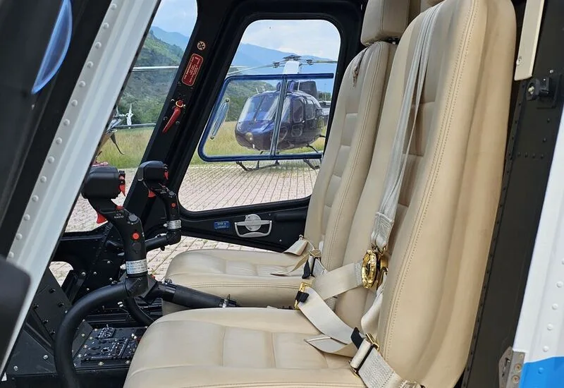 Cockpit view of the AgustaWestland AW109 helicopter with beige leather seats.