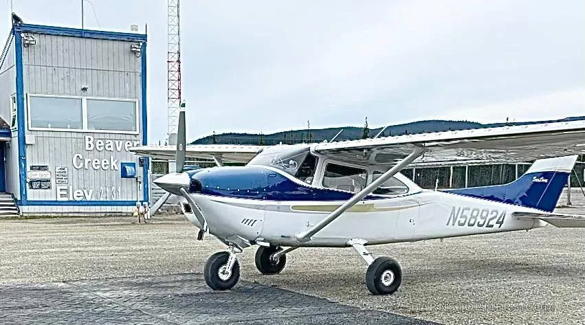 A white and blue Cessna 182 Skylane (N58924) parked on an airfield next to a building labeled "Beaver Creek".