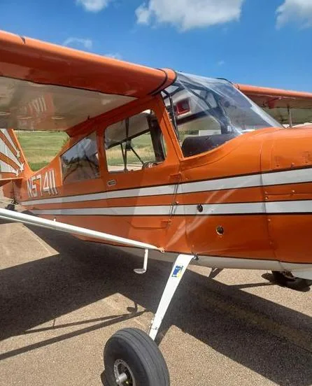 A close-up side view of the orange N57411 aircraft, showing the cockpit windows and white stripe details.