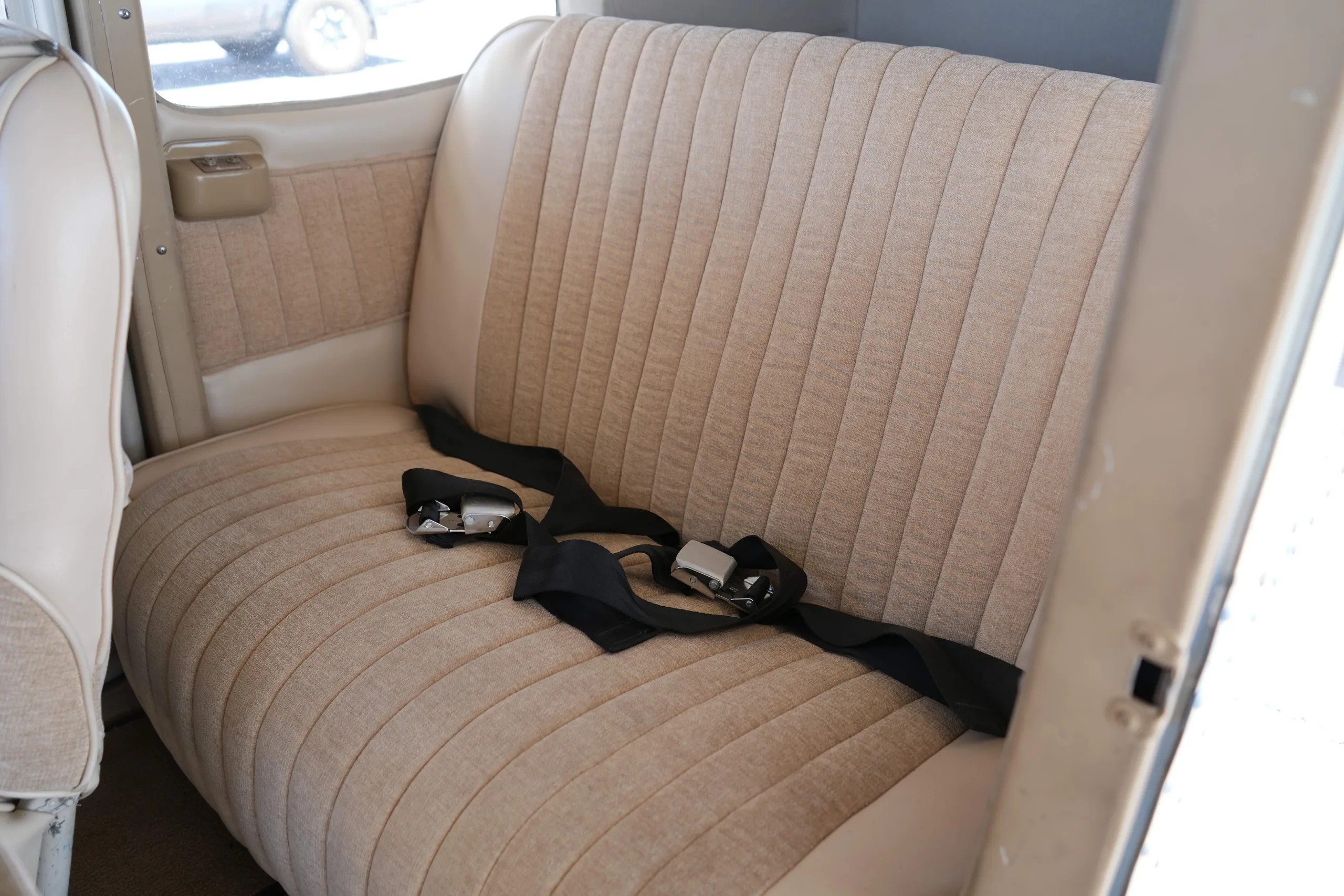 View of the beige rear bench seat with seatbelts in the cabin of a Cessna 172.