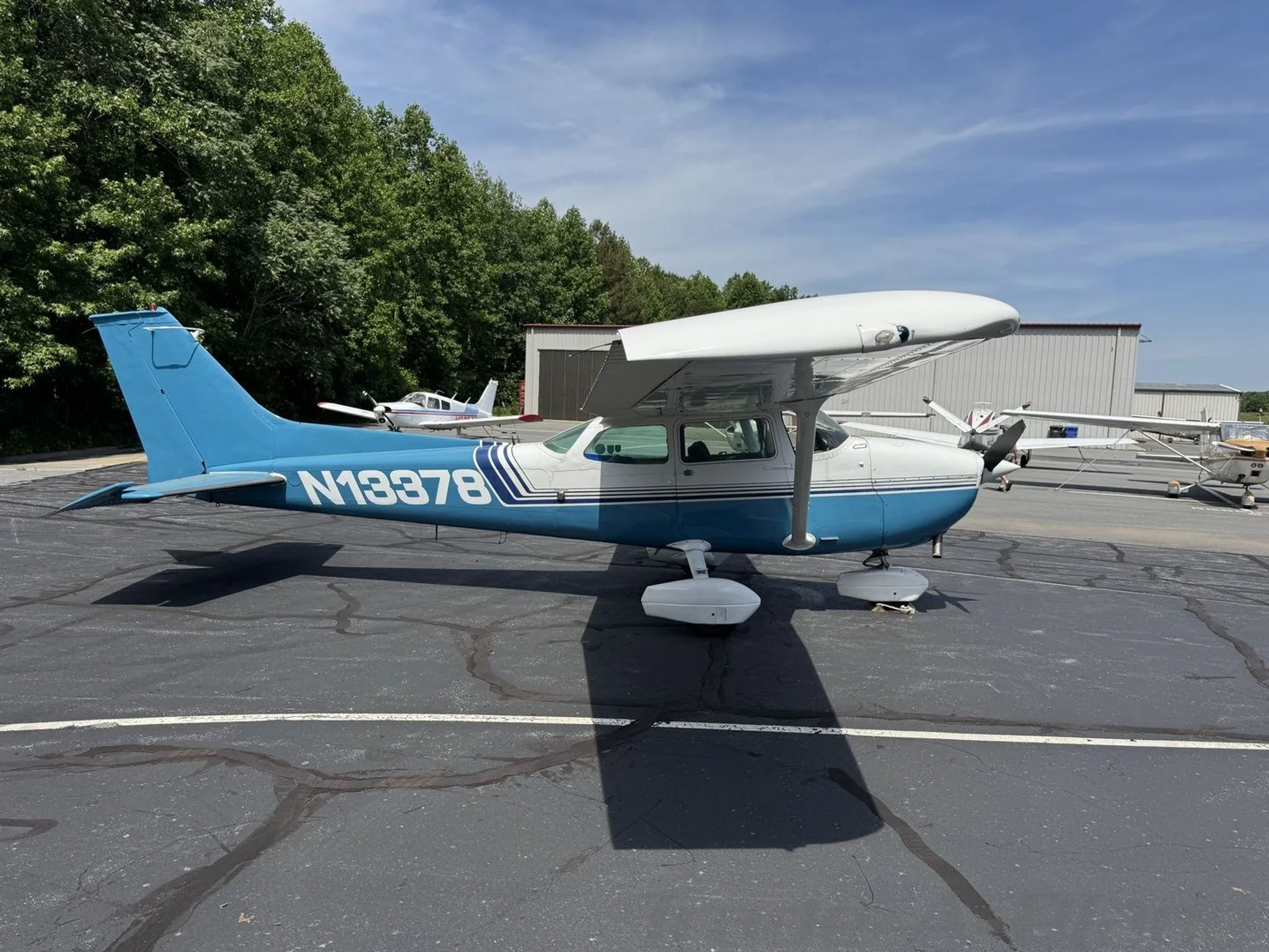 A side-right view of the blue and white Cessna 172 Skyhawk (N13378) parked on an asphalt apron.