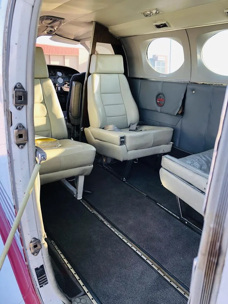 View into the aircraft cabin from the open door, showing light gray seats and a dark carpeted aisle.