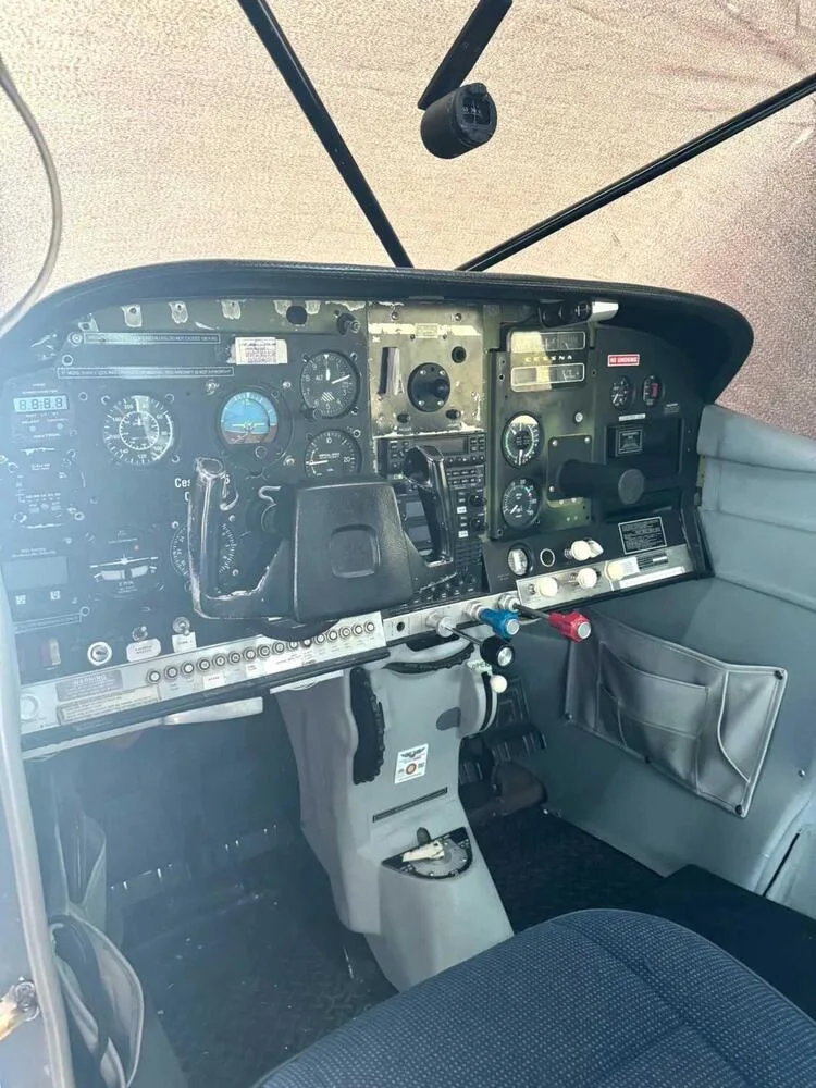 The cockpit of a small aircraft, showing the instrument panel, yoke, and controls from a low angle.